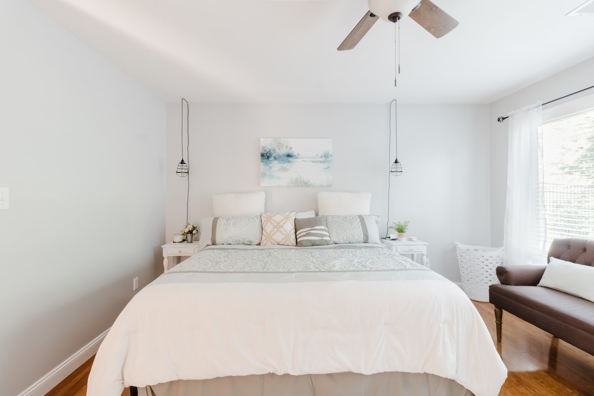 Bright king bedroom with sitting area and polished hardwood floors
